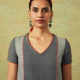 Close up of the V-neck line of Patchwork dress in shades of grey with bold orange side pocket – RA Studio