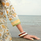 Person wearing a floral dress and bangles by the sea