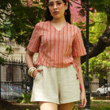 Woman wearing a red and white striped top and beige shorts in a park setting.