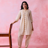 Beige cotton Mangalgiri co-ord with a front-pleated button kurta and contrast top stitching on the kurta and pant hems.