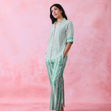 Green cotton co-ord with a thin-stripe block-print collared tunic shirt, turn-up sleeves and wide-stripe flared pants.