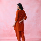 Red cotton Mangalgiri co-ord with a front-pleated, contrast-stitched kurta and button-and-cotton-bell pant hems.