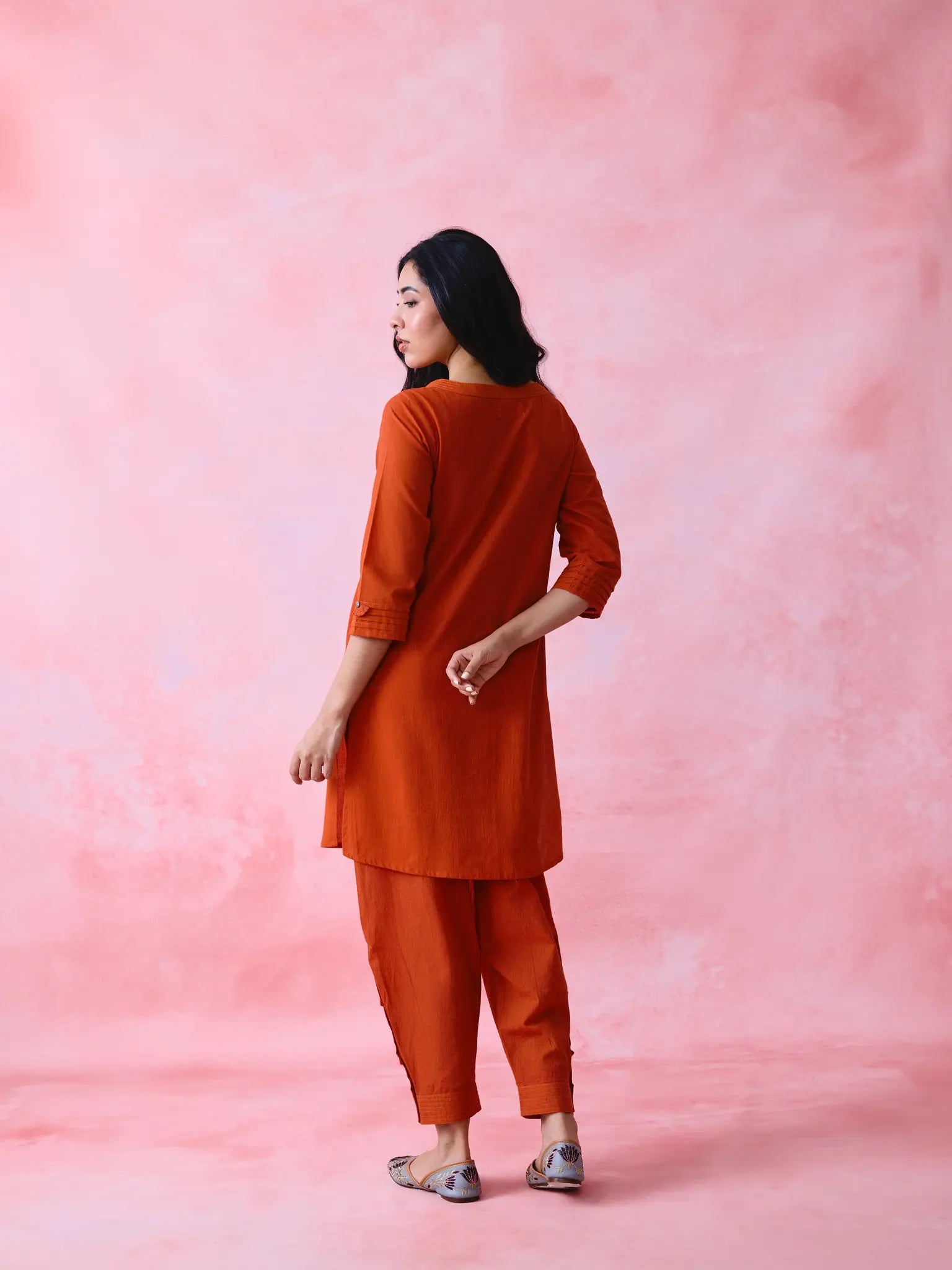 Red cotton Mangalgiri co-ord with a front-pleated, contrast-stitched kurta and button-and-cotton-bell pant hems.