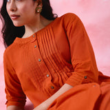 Red cotton Mangalgiri co-ord with a front-pleated, contrast-stitched kurta and button-and-cotton-bell pant hems.