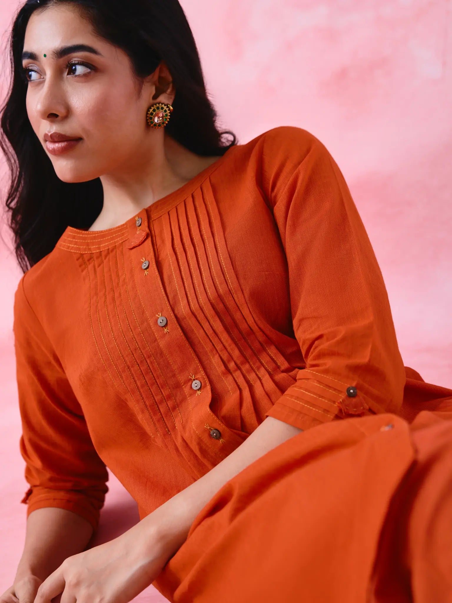Red cotton Mangalgiri co-ord with a front-pleated, contrast-stitched kurta and button-and-cotton-bell pant hems.
