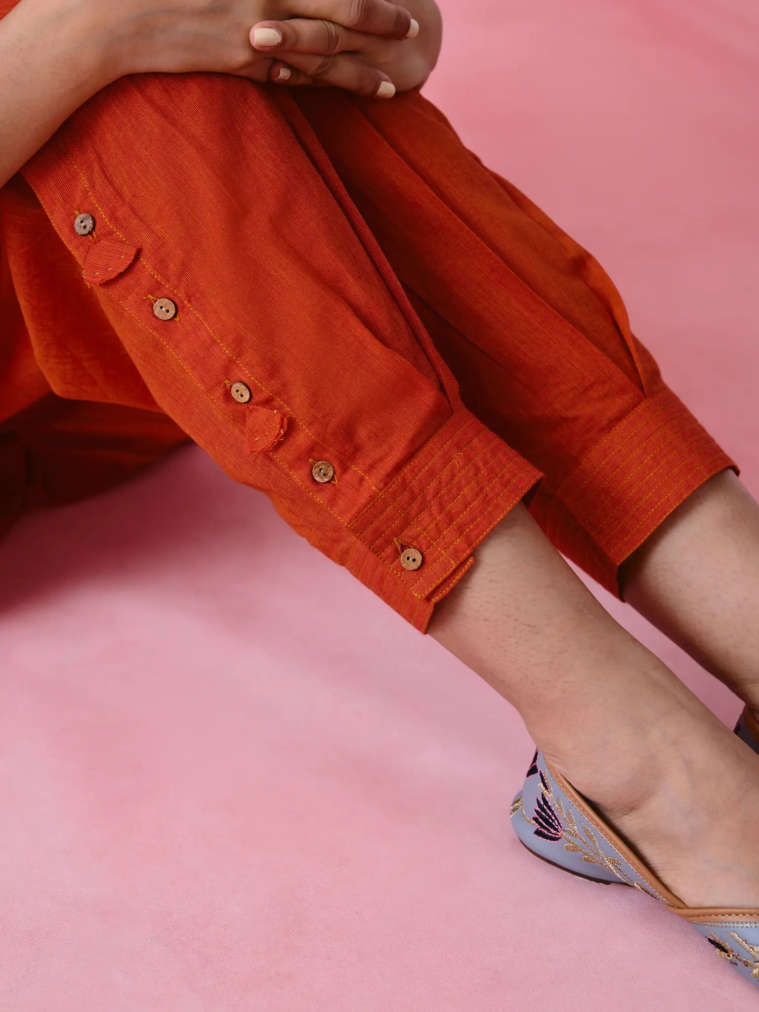 Red cotton Mangalgiri co-ord with a front-pleated, contrast-stitched kurta and button-and-cotton-bell pant hems.