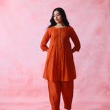 Red cotton Mangalgiri co-ord with a front-pleated, contrast-stitched kurta and button-and-cotton-bell pant hems.