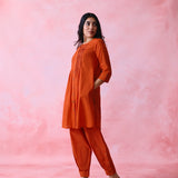 Red cotton Mangalgiri co-ord with a front-pleated, contrast-stitched kurta and button-and-cotton-bell pant hems.