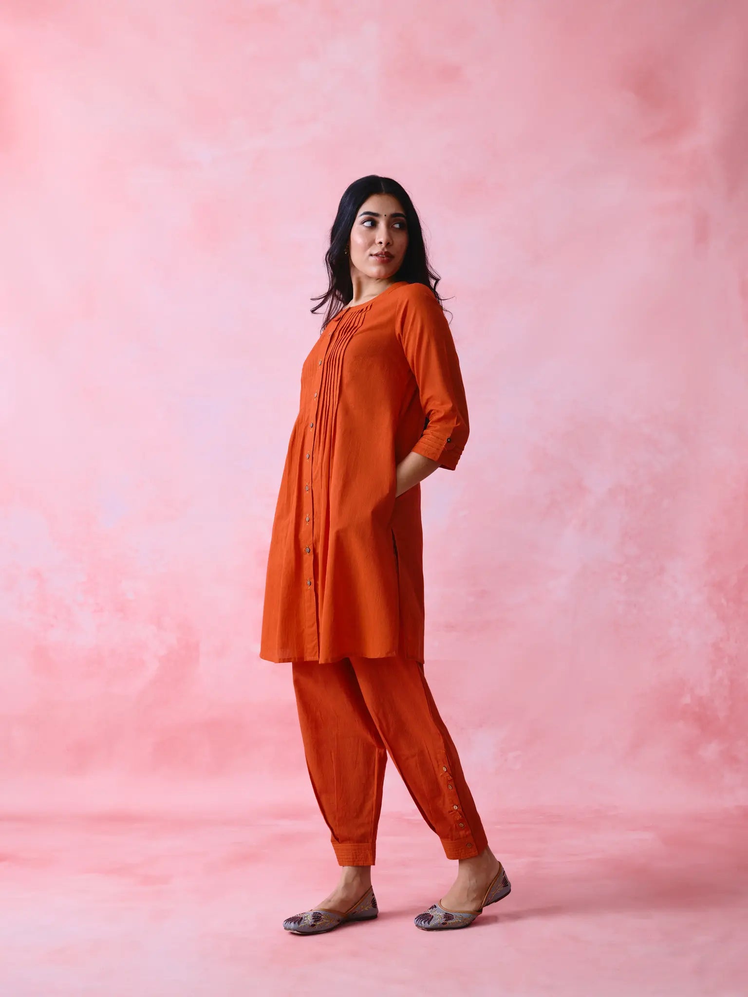 Red cotton Mangalgiri co-ord with a front-pleated, contrast-stitched kurta and button-and-cotton-bell pant hems.