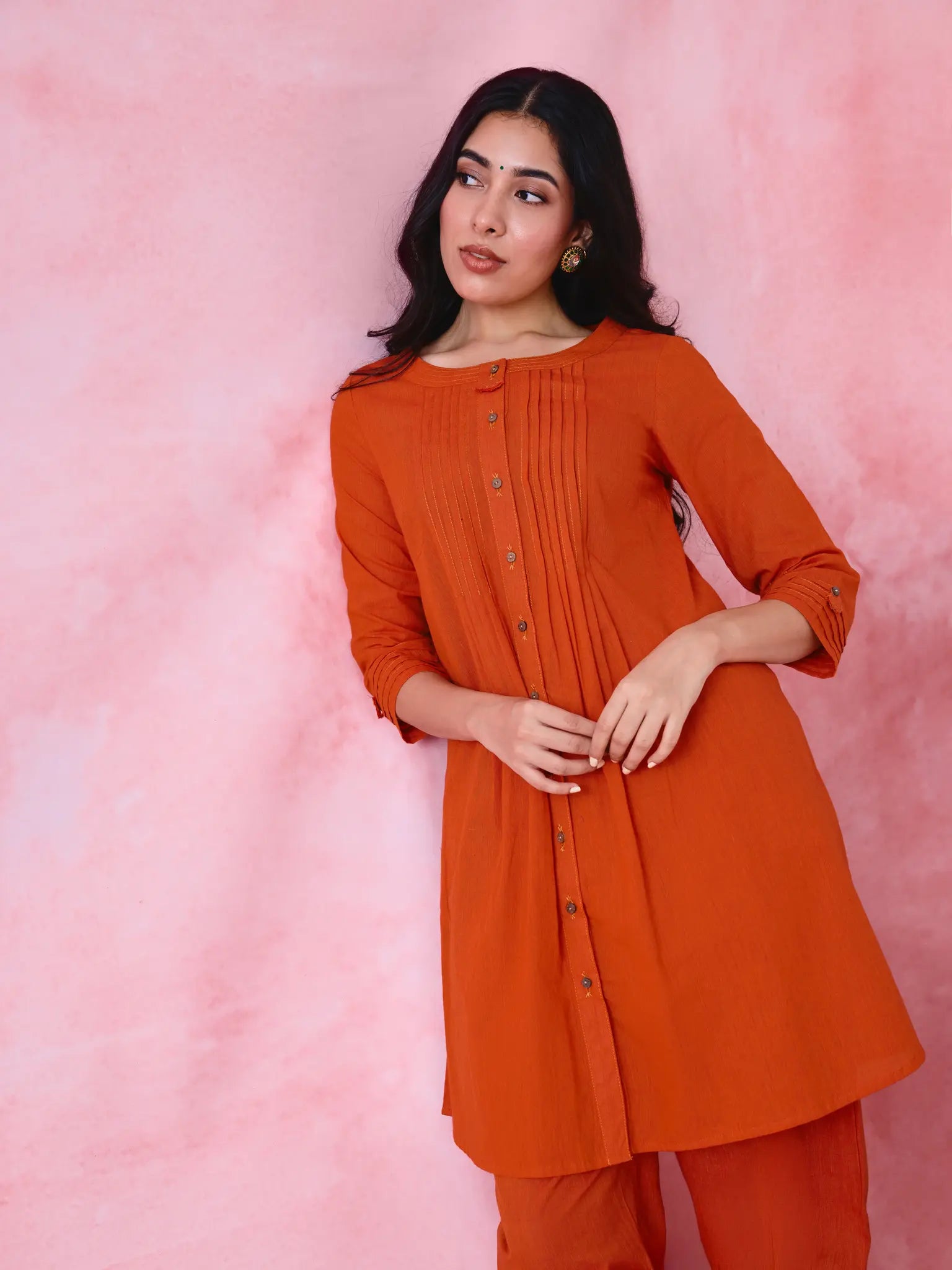 Red cotton Mangalgiri co-ord with a front-pleated, contrast-stitched kurta and button-and-cotton-bell pant hems.