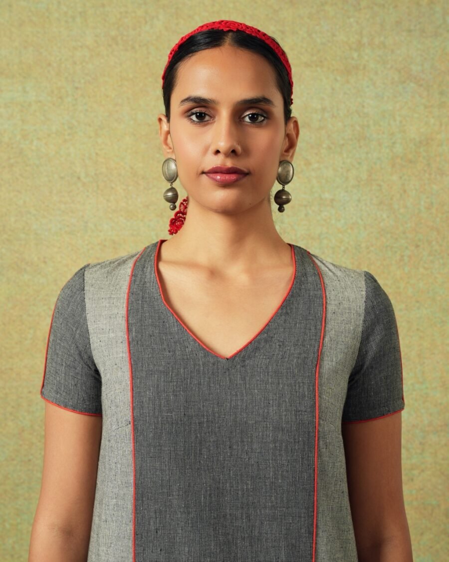 Close up of the V-neck line of Patchwork dress in shades of grey with bold orange side pocket – RA Studio